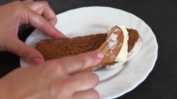 Woman hands with wooden kife are Spreading soft butter on a piece of bread. — Stock Video