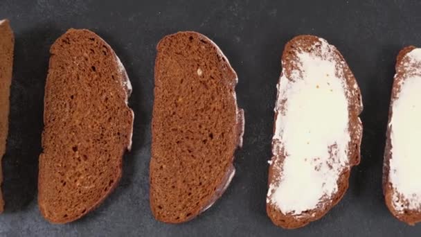 Pão artesanal fatiado cozido no forno fresco com manteiga em um fundo escuro — Vídeo de Stock