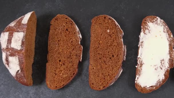 Pâine artizanală proaspăt coaptă feliată cu unt pe un fundal întunecat — Videoclip de stoc