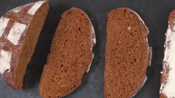 Frisch gebackenes handwerklich geschnittenes Brot mit Butter auf dunklem Hintergrund — Stockvideo