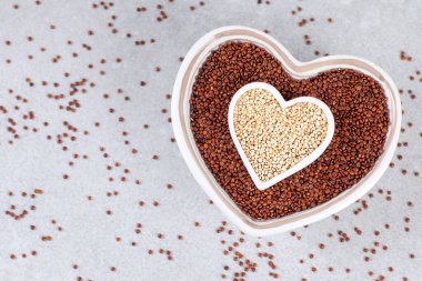 Taş zemin üzerinde kalp şeklinde bir kase içinde kırmızı ve beyaz kinoa.