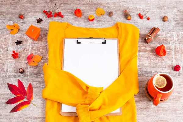 Maglione giallo con appunti intorno alla candela, foglie secche, tè — Foto Stock