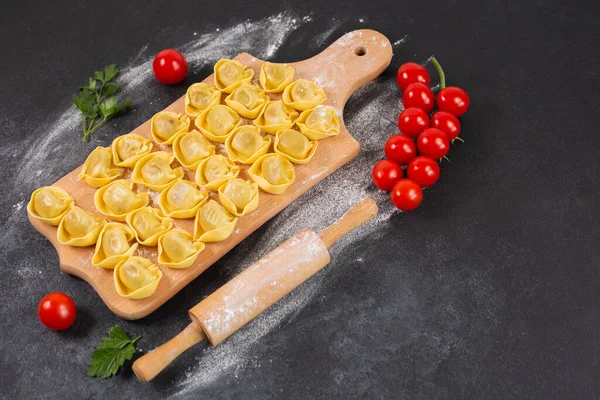 Tortelloni niegotowane z nadzieniem grzybkowym na drewnianej desce. — Zdjęcie stockowe