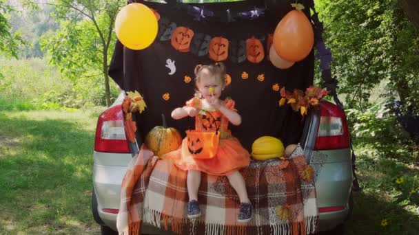 Little Kid menina Halloween, sentado no porta-malas do carro e comer doces de baldes. — Vídeo de Stock