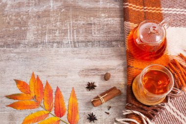 Kareli turuncu ekose ve çay fincanı olan masa, sonbahar yaprakları.