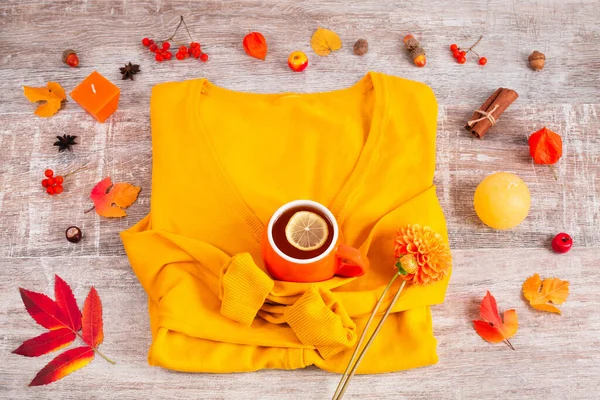 Cardigan giallo del maglione e tazza di tè caldo intorno alla candela, foglia secca — Foto Stock