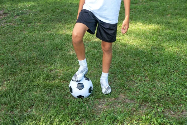 Jongen tiener zet zijn been op bal op voetbalveld. — Stockfoto