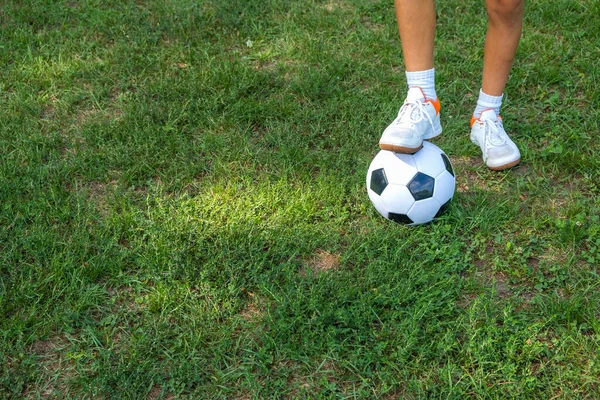 Menino adolescente coloca sua perna na bola no campo de futebol. — Fotografia de Stock