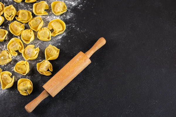 Ungekochte Tortelloni mit Pilzfüllung auf schwarzem Hintergrund, — Stockfoto