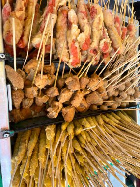 Şişler üzerinde leziz ve kızartılmış sokak yemekleri, sosisler, çıtır çıtır soya peyniri ve tuzlu börekler dahil, açık hava tezgahında satılmak üzere güzelce düzenlenmiştir.