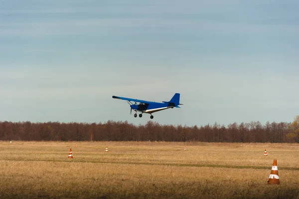 Een klein sportvliegtuig van blauwe kleur stijgt op vanaf het vliegveld in het veld. — Stockfoto
