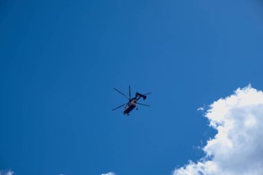  Bulutlu mavi gökyüzüne karşı bir helikopter silueti. Ulaştırma servisi. Teknoloji geçmişi.