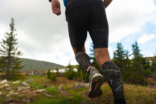 A runner without gender differences in the mountains. The athlete goes to victory in spite of rain and mud.