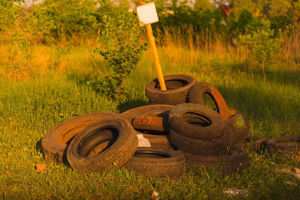 Dump of tires with a sign in the forest.