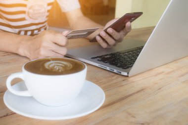 Adam smartphone dizüstü kullanarak ve kredi kartı ile s tutan eller