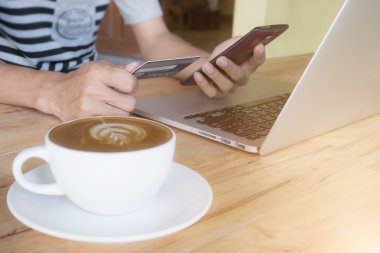 Adam smartphone dizüstü kullanarak ve kredi kartı ile s tutan eller