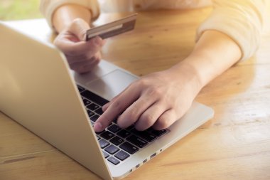 Bir kredi kartı tutan ve online alışveriş için pc veya dizüstü bilgisayar kullanarak adamın elleri.