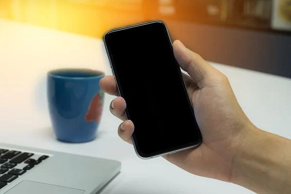 Primer plano de un hombre que utiliza el teléfono inteligente con el móvil en blanco y la taza de —  Fotos de Stock