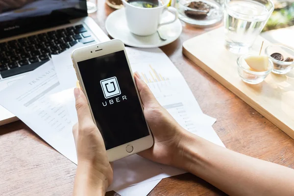 Chiang Mai,Tayland - 09 Mayıs 2015 : Iphone 6 plus'ta kafede gösterilen Uber uygulamasını tutan bir kadın, Uber akıllı telefon uygulaması tabanlı ulaşım ağıdır.