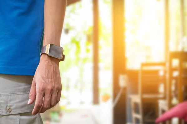 Young man wears smart watch in coffee shop.