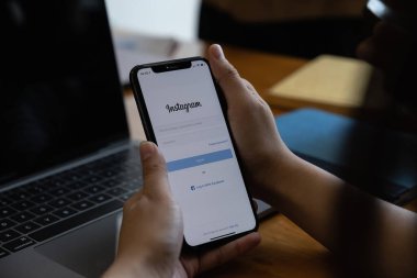 CHIANG MAI, THAILAND - 19 MAR 2021: Instagram uygulamasının giriş ekranı ile iPhone 'u tutan bir kadın. Instagram en büyük ve en popüler sosyal ağdır..