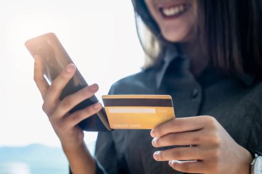 İnternetten alışveriş. Çevrimiçi alışveriş için akıllı telefon klavyesiyle kredi kartı bilgilerini yazan Asyalı kadın.