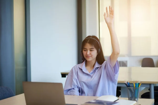 Happy student wave hand and have question while learning online sitting in living room from home by laptop computer. Social distancing.stay home. New normal.Covid-19 coronavirus.