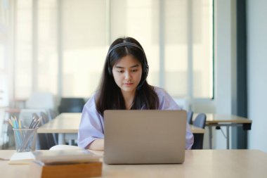 Çocuklar evlerinden dizüstü bilgisayarlarıyla oturma odalarında kablosuz kulaklık öğrenme dersleri alıyorlar. Sosyal uzaklık. Evde kal. Yeni normal. Covid-19 koronavirüs..