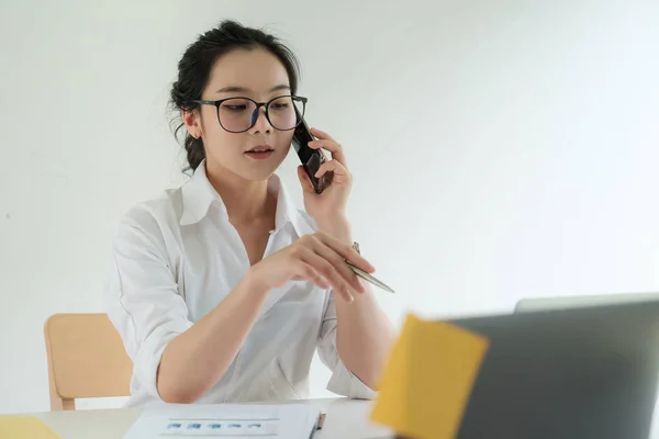 忙しいビジネスの女性はビデオ通話や携帯電話との会話で沈黙と話し合います。コールセンターのノートパソコンで仕事をしている間に顧客に説明しようとする女性技術サポートエージェント. — ストック写真