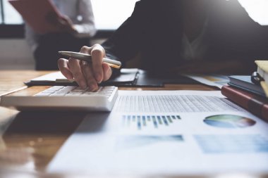 Proje yönetimi ekibi evrak işleri ile ilgili finansal grafikleri güncelliyor ve hesaplıyor..