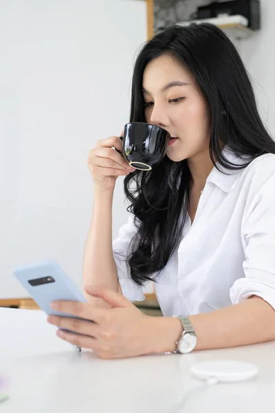 아침에 커피를 마시면서 항구 주식 시장을 점검하는 아시아 여성 재계의 모습. — 스톡 사진
