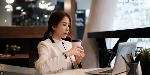 El pensamiento ejecutivo femenino sobre el horario de trabajo para el informe de la escritura del empleado en el ordenador portátil digital en espacio de coworking. —  Fotos de Stock