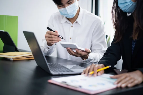 Business People wear mask at meeting to discuss and brainstorming the financial report paperwork in home office. Financial advisor teamwork and accounting concept