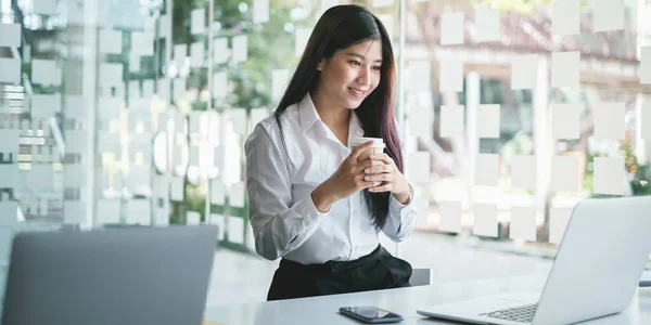 El pensamiento ejecutivo femenino sobre el horario de trabajo para el informe de la escritura del empleado en el ordenador portátil digital en espacio de coworking. — Foto de Stock