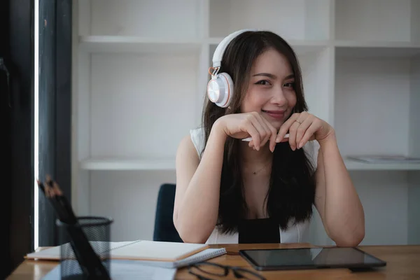 Μια χαρούμενη γυναίκα με ακουστικά επικεντρώνεται σε ένα webinar στον φορητό υπολογιστή της. — Φωτογραφία Αρχείου