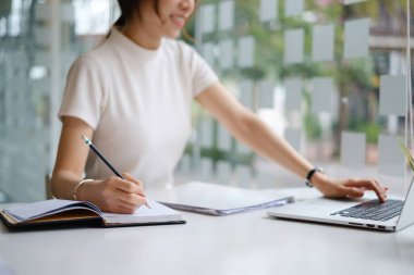 Genç bayan kolej notlar alıyor ve fosforlu kalem kullanıyor. Çevrimiçi sınıf odasında odaklanmış bir öğrenci. Otantik Eğitim kavramı.