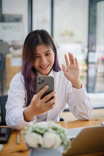 Χαρούμενη επιχειρηματίας που κάθεται στο γραφείο κοιτάζοντας κάμερα smartphone μιλώντας με φίλο κάνει ανεπίσημη κλήση βίντεο. — Φωτογραφία Αρχείου