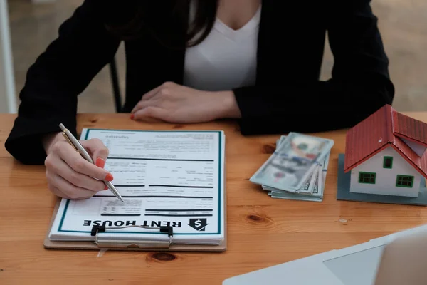 Following a deal with a broker, a woman signs a contract to rent a house — Stock Photo, Image