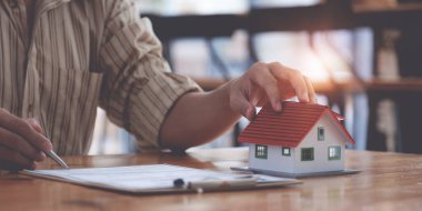 Müşteri bulmadan önce ev modeli ve sözleşmesi olan bir emlakçı. Özellik kavramı.