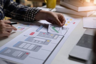 Mobil bir uygulama için bir model simgesi arayüzü üzerinde çalışan bir ux ui geliştiricisi ve bir ui tasarımcısının yakın plan görüntüsü.
