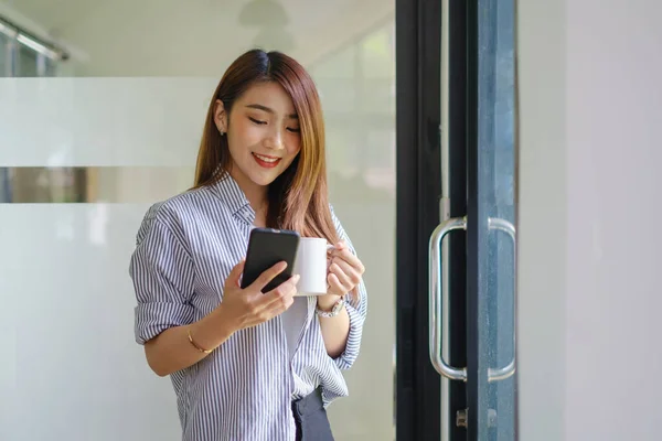 Ung vacker kvinna som håller kaffekopp och känner sig fräsch när hon sitter på sin arbetsplats på måndag morgon. — Stockfoto