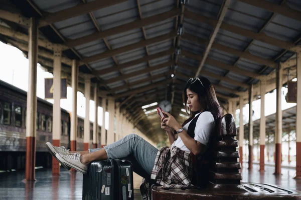 Bild einer Reisenden, die die Nachricht ihres Freundes checkt und am Bahnhof wartet. Reisekonzept — Stockfoto