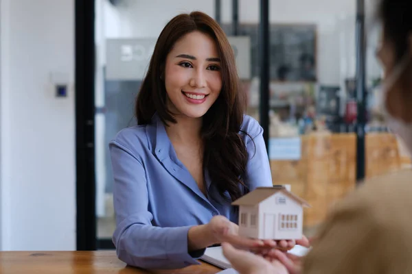 En fastighetsmäklare visar huset modell för kunder som är intresserade av att köpa husförsäkring. Begreppet hemförsäkring och egendom. — Stockfoto