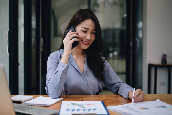 Mujer de negocios hacer contabilidad financiera mercado de valores gráficos de análisis de papeleo y discutir con su equipo por teléfono celular en la oficina. — Foto de Stock