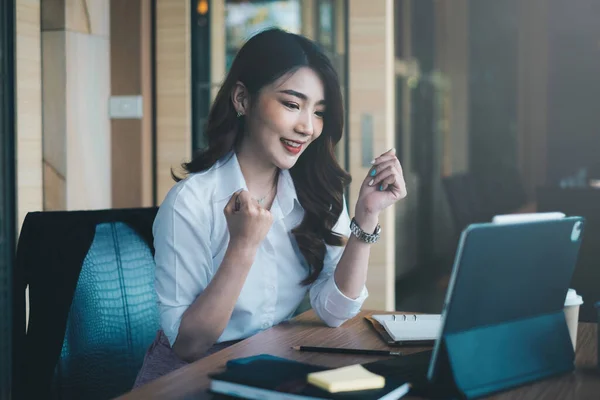 Podekscytowana azjatycka kobieta siedzi na swoim stanowisku pracy, zachwycona otrzymaniem oferty pracy po wywiadzie mailowym na laptopie — Zdjęcie stockowe