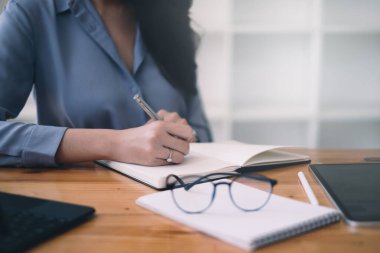 Genç lisans öğrencisi dizüstü bilgisayarla online ders çalışıyor ve not alıyor.