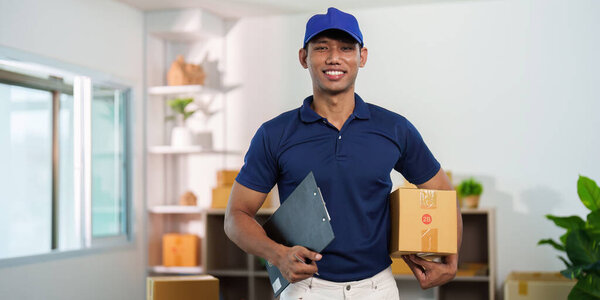 A cheerful delivery man stands in a bright office, showcasing his role in logistics and package delivery services.