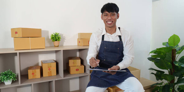 A cheerful employee sits in a logistics office, jotting down notes and managing tasks related to package delivery.