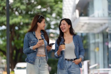 İki arkadaş neşe dolu bir anı paylaşıyor. Canlı bir şehir ortamında kahve içip sohbet ediyorlar. Arkadaşlık ve dostluk gösteriyorlar..