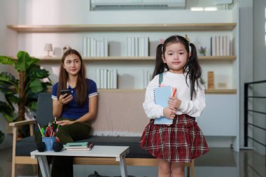 Genç bir kız okul malzemelerini elinde tutuyor. Öğrenmeye hazır olduğunu gösteriyor..